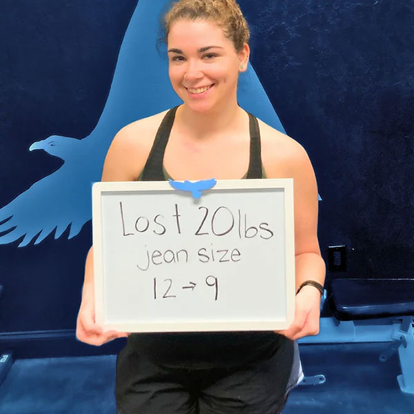 Woman holding a sign that reads "Lost 20lbs jean size 12 to 9"